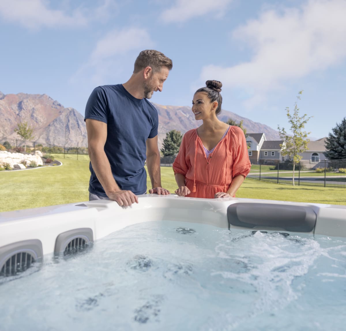 Two people are standing beside a hot tub looking at each other.